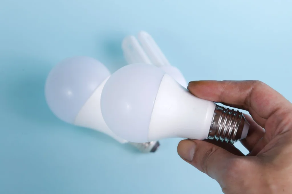 Mano sosteniendo bombillas LED de bajo consumo: elegir por lúmenes y eficacia, no por watts